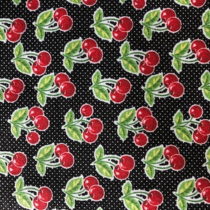 May include: Black fabric with a repeating pattern of red cherries on green stems. The background is a black fabric with white polka dots.