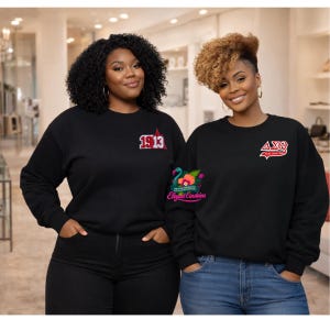 May include: Two women wearing black sweatshirts with embroidered logos. One sweatshirt has "1913" in red and white, the other has a red and white Greek letter design. Both sweatshirts have long sleeves and are black.