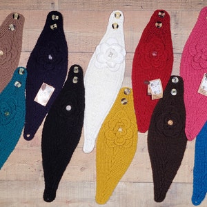 May include: Ten knitted headbands with a flower design. The headbands are in various colors, including brown, teal, black, white, red, yellow, brown, and blue.
