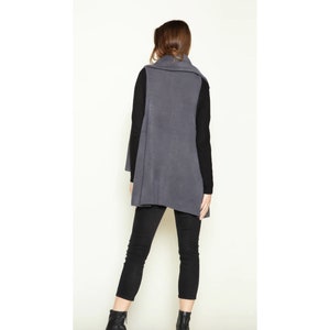 May include: A long, charcoal gray, open-front vest with a draped collar. The vest is made of a soft, knit fabric.