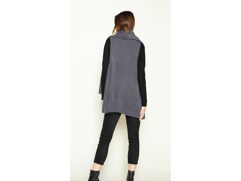 May include: A long, charcoal gray, open-front vest with a draped collar. The vest is made of a soft, knit fabric.