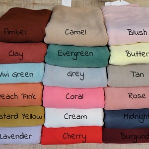 May include: A stack of 18 fabric swatches in various colors, including amber, camel, blush, clay, evergreen, butter, vivi green, grey, tan, peach pink, coral, rose, mustard yellow, cream, midnight, lavender, cherry, and burgundy.