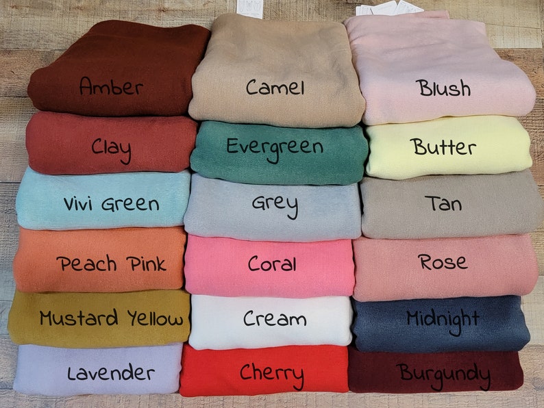 May include: A stack of 18 fabric swatches in various colors, including amber, camel, blush, clay, evergreen, butter, vivi green, grey, tan, peach pink, coral, rose, mustard yellow, cream, midnight, lavender, cherry, and burgundy.
