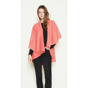 May include: A coral pink wrap with a draped design. The wrap is made of a soft, lightweight fabric and is perfect for layering over a simple outfit.