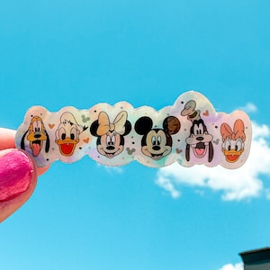 May include: A set of six colorful character stickers featuring Mickey Mouse, Minnie Mouse, Donald Duck, Goofy, and Pluto. The stickers are on a white background with a light blue sky in the background.