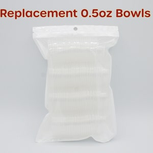 May include: A clear plastic bag containing a large number of small, clear plastic bowls. The bag is labelled "Replacement 0.5oz Bowls".
