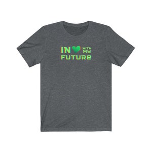 Op de afbeelding: Een donker grijs t-shirt met een groen hart en de tekst "IN &hearts; WITH MY FUTURE" in een regenboogkleurige gradi&euml;nt.