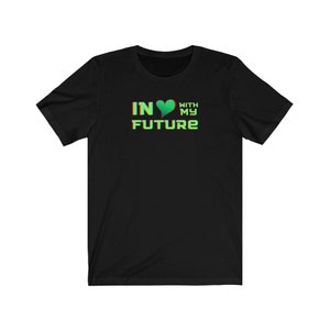 Op de afbeelding: Zwart T-shirt met een groen hart en de tekst "IN &hearts; WITH MY FUTURE" in een groen en rood lettertype.
