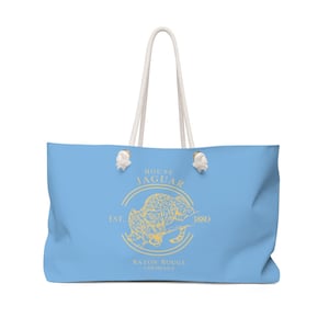 May include: A light blue tote bag with white rope handles. The bag has a yellow graphic of a jaguar with the text "House Jaguar Est. 1880 Baton Rouge, Louisiana".