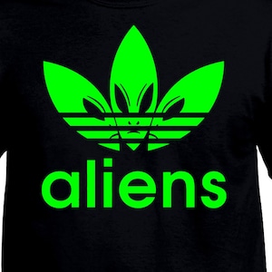 May include: A black t-shirt with a green alien-shaped Adidas logo and the word "aliens" printed below it.