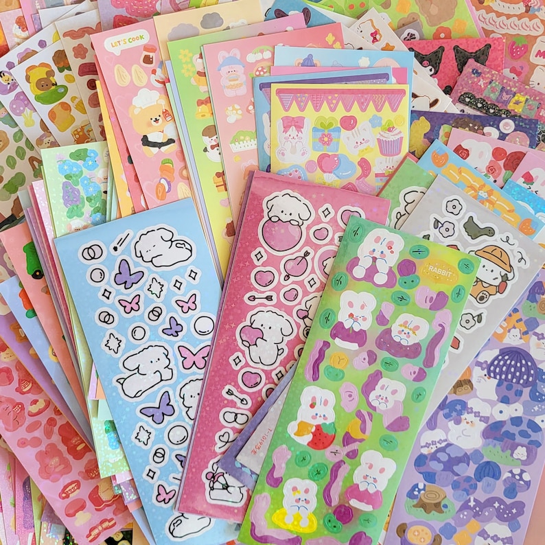May include: A collection of colorful sticker sheets featuring various designs, including cute animals, hearts, stars, and other whimsical elements. The stickers are perfect for adding a touch of personality to journals, planners, laptops, and other items.