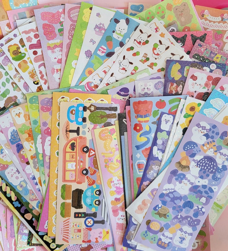 May include: A collection of colorful sticker sheets featuring various themes, including animals, transportation, and food. The stickers are printed on white paper and have a glossy finish.