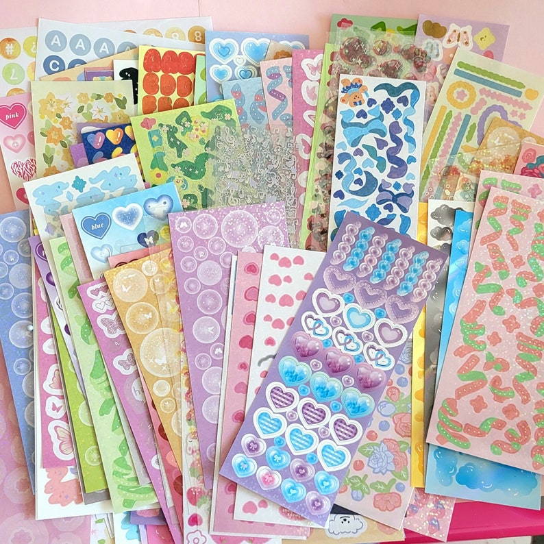 May include: A large collection of colorful sticker sheets featuring various designs, including hearts, stars, flowers, and geometric patterns. The stickers are perfect for decorating journals, planners, and other craft projects.