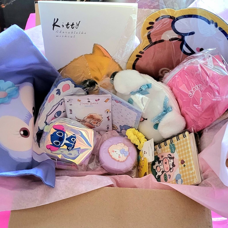 May include: A pink and white gift box filled with various items, including a plush toy, a notepad, a small pouch, and a sticker sheet. The box is decorated with pink tissue paper and a white card that reads "Kitty Adorable Wishcal".
