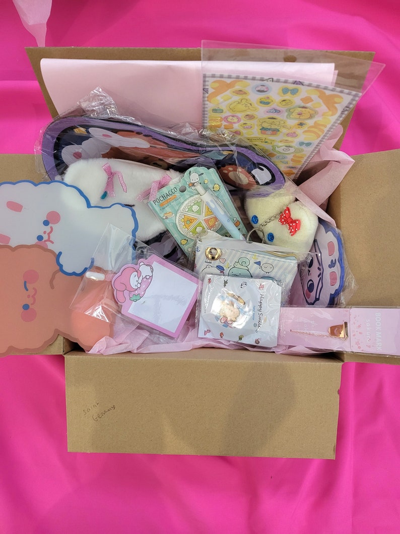 May include: A brown cardboard box filled with various items, including a pink and white plush toy, a sticker sheet, a small notebook, and a keychain. The box is decorated with a pink and white tissue paper and has the words "So much cuteness" written on the bottom.