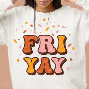 May include: A white sweatshirt with the text "FRI-YAY" in retro-style lettering with orange, pink, and brown colors. The text is surrounded by confetti and stars.