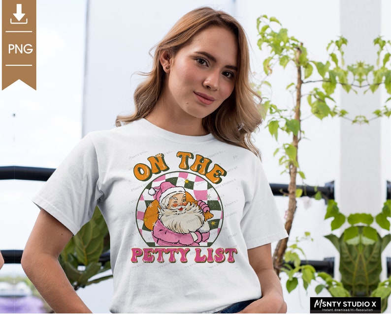 May include: White t-shirt with a pink and green graphic of Santa Claus with the text "On the Petty List".