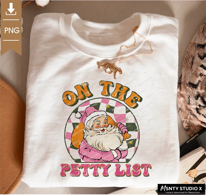 May include: A white sweatshirt with a pink and green graphic design featuring a cartoon Santa Claus holding a bag of gifts. The graphic says "On the Petty List".