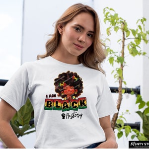 K&ouml;nnte beinhalten: Ein wei&szlig;es T-Shirt mit einem Grafikdesign, das ein Cartoon-M&auml;dchen mit Afro-Frisur zeigt. Das Design enth&auml;lt die Worte "I am Black History" und eine geballte Faust.