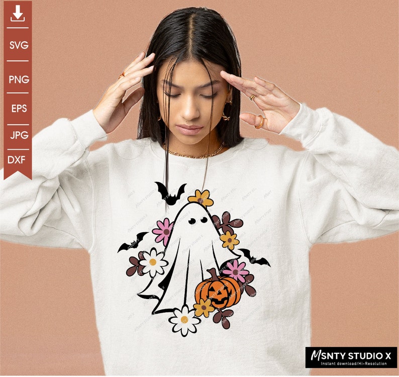 Pu&ograve; includere: Un fantasma bianco con un viso amichevole circondato da fiori arancioni, rosa e gialli e pipistrelli. Il fantasma tiene una zucca intagliata a forma di zucca.