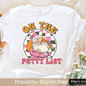 May include: A white t-shirt with a pink and green graphic of Santa Claus with the text "On the Petty List".