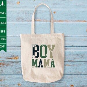 Pu&ograve; includere: Una borsa tote in tela bianca con il testo "BOY MAMA" in lettere verdi, nere e bianche. Le lettere sono riempite con un motivo mimetico di dinosauri verdi e neri.
