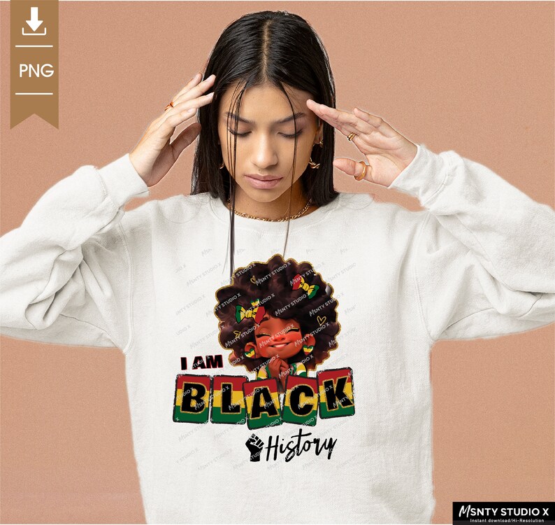 K&ouml;nnte beinhalten: Ein wei&szlig;er Pullover mit einem Grafikdesign, das ein schwarzes Cartoon-M&auml;dchen mit einer rot-gelb-gr&uuml;nen Afrofrisur zeigt. Der Text "I AM BLACK History" ist in schwarzen Buchstaben auf dem Pullover gedruckt.