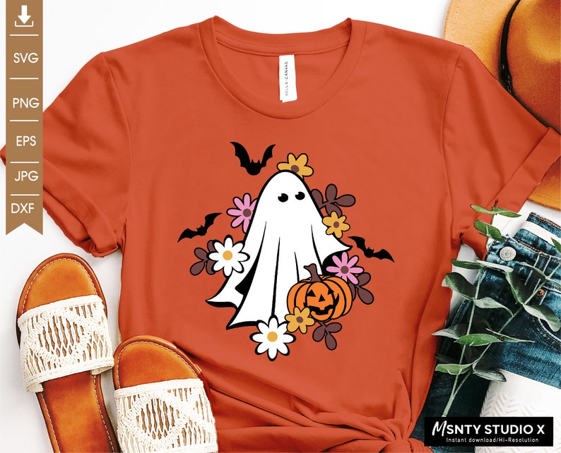 Pu&ograve; includere: Una maglietta arancione con un fantasma bianco che tiene una zucca di Halloween circondata da fiori e pipistrelli.