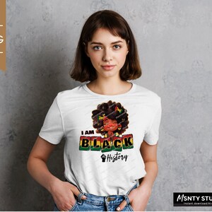 K&ouml;nnte beinhalten: Wei&szlig;es T-Shirt mit einem Aufdruck einer schwarzen Frau mit Afro und dem Text "I AM BLACK History" in roten, gr&uuml;nen und gelben Bl&ouml;cken.