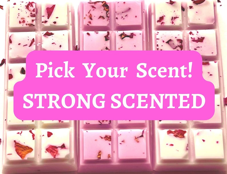 May include: Three rectangular wax melt bars with a pink banner that reads "Pick Your Scent! STRONG SCENTED". The bars are divided into individual squares, some are white, some are pink, and all are decorated with dried flower petals.