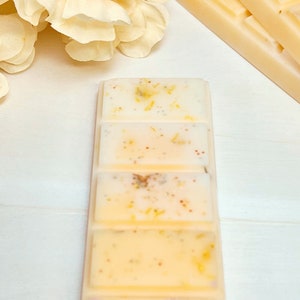 Puede incluir: Un juego de cinco fundidos de cera en forma rectangular. Los fundidos de cera son de color amarillo claro con motas de purpurina dorada. Los fundidos de cera est&aacute;n apilados.