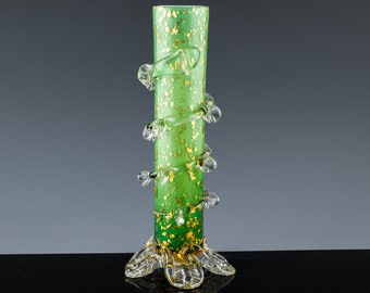 May include: A green glass vase with gold flecks and clear glass swirls. The vase has a wide base and a narrow neck.