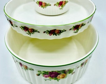 May include: A two-tiered serving dish with a floral pattern. The top tier is a smaller bowl, and the bottom tier is a larger bowl. Both bowls have a green rim.