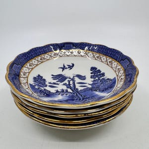 Puede incluir: Un conjunto de seis platillos de porcelana azul y blanco con borde dorado y diseño de sauce.