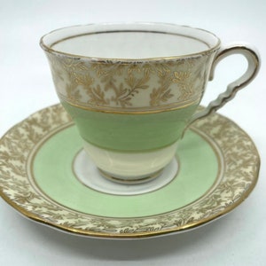 May include: A green and white teacup and saucer set with gold trim and a floral pattern.