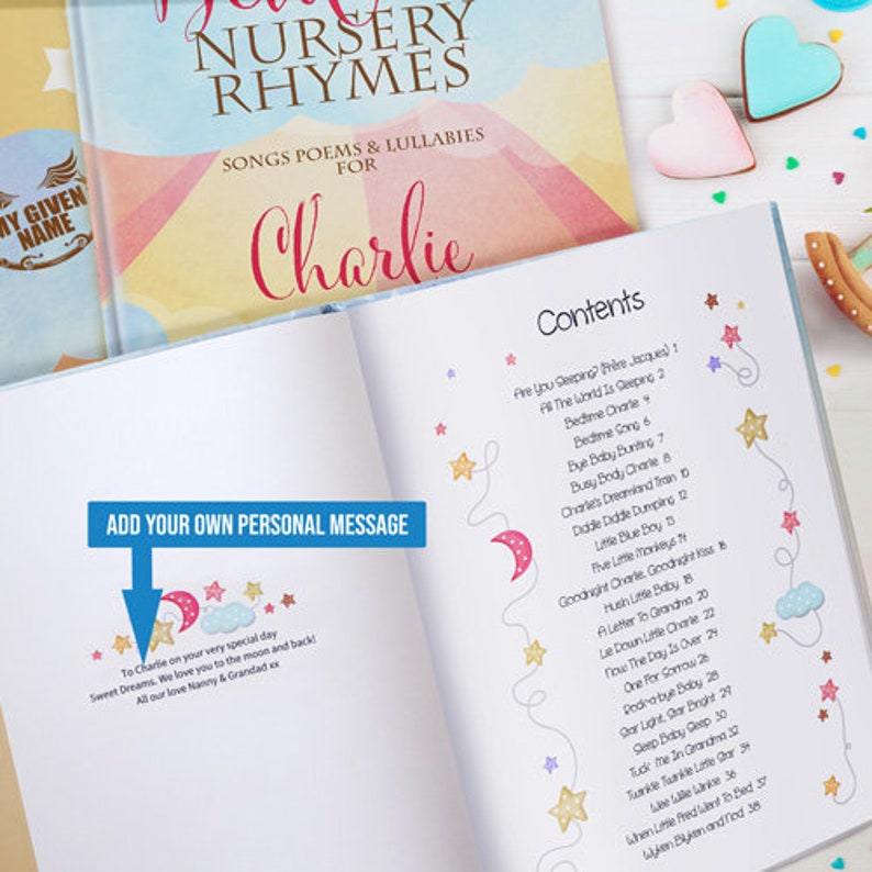 May include: A personalised nursery rhyme book with a blue and pink cover featuring stars and moons. The book is titled "Nursery Rhymes" and has the name "Charlie" printed on the cover. The book has a contents page with a list of nursery rhymes.