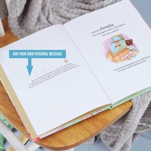 Pode incluir: Um livro infantil personalizado com um design floral rosa e verde. O livro est&aacute; aberto em uma p&aacute;gina com uma mensagem escrita &agrave; m&atilde;o que diz "To our beautiful Amelia on your 3rd Birthday A gift you can open again and again to bring you joy! All our love Aunty Margaret, Uncle Freddie & Sweep xxx". A p&aacute;gina seguinte tem uma ilustra&ccedil;&atilde;o de uma menina olhando para fora de uma janela e o texto "Dearest Amelia, Can you guess when and where our story starts? It was the evening before the 18th April, in a place called Camden Green..."