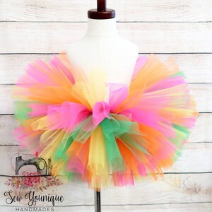 Puede incluir: Una falda de tut&uacute; de tul multicolor en tonos rosa, naranja, amarillo y verde. La falda es llena y esponjosa, y ser&iacute;a perfecta para una fiesta de cumplea&ntilde;os o una ocasi&oacute;n especial para una ni&ntilde;a.