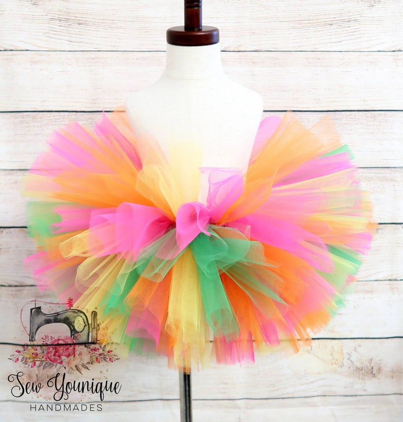 Puede incluir: Una falda de tut&uacute; de tul multicolor en tonos rosa, naranja, amarillo y verde. La falda es llena y esponjosa, y ser&iacute;a perfecta para una fiesta de cumplea&ntilde;os o una ocasi&oacute;n especial para una ni&ntilde;a.