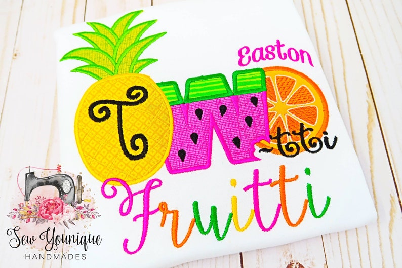 Puede incluir: Dise&ntilde;o bordado con una pi&ntilde;a, una sand&iacute;a y una naranja con el texto "Two Fruitti" y el nombre "Easton".