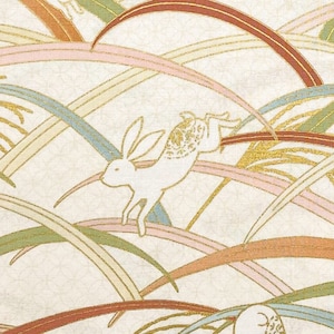 May include: White rabbits hopping through a field of gold, pink, green, and brown grass. The background is a cream color with a subtle texture. "SEWN IN SEATTLE" is printed at the bottom of the image.