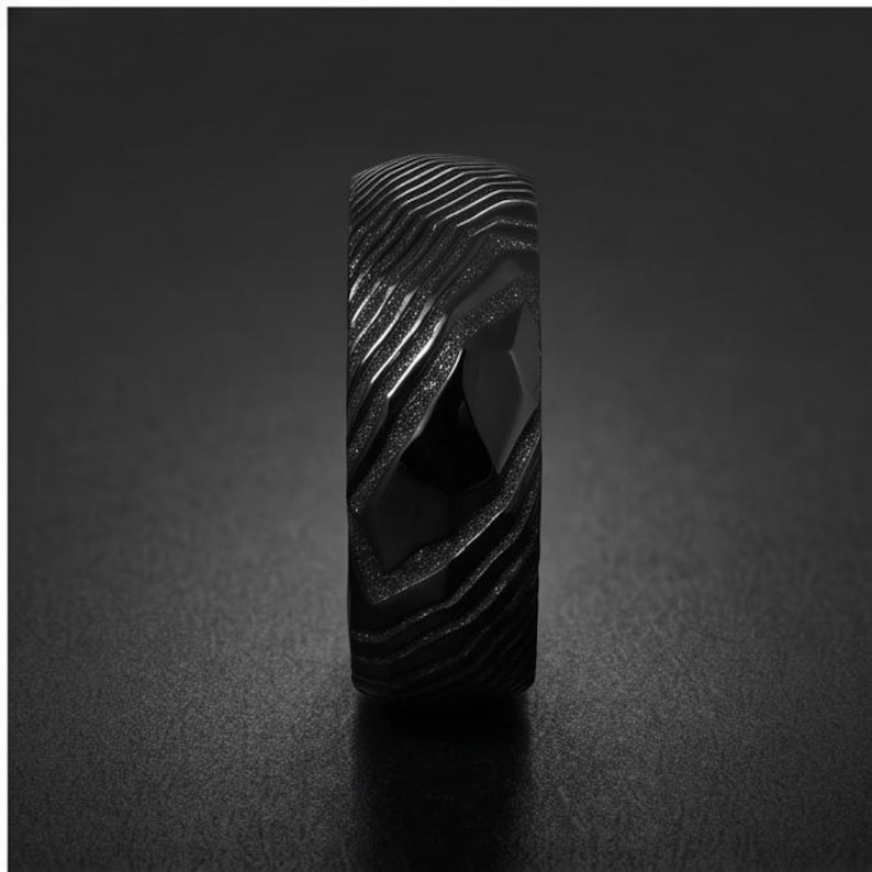 May include: A black ring featuring a textured surface with deep, wavy grooves and a matte finish. The band displays a complex, layered pattern that resembles topographical lines, creating a dark, dimensional appearance across the entire exterior.