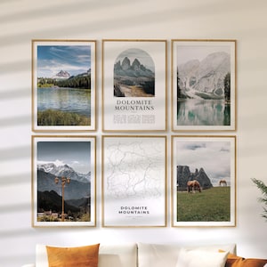 May include: Six framed landscape prints featuring mountain and lake scenes. Two prints include the text "Dolomite Mountains Italy". The prints are in wooden frames and are displayed on a white wall above an orange couch.