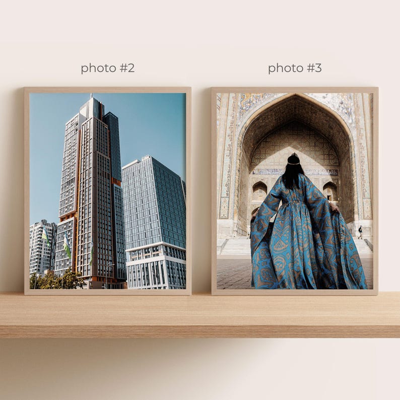 May include: Two framed photographs on a wooden shelf. The left photo shows modern skyscrapers against a blue sky. The right photo features a person in a blue patterned dress standing in front of an arched doorway.