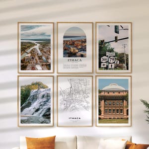 May include: Six framed art prints with wooden frames. The prints feature scenic views of Ithaca, New York, including a map, a waterfall, and cityscapes. The prints are displayed on a white wall above an orange couch.