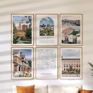 May include: Six framed art prints featuring images of Columbus, Ohio. The prints include cityscapes, a map, and architectural views. The frames are a light brown color, and the prints are displayed on a white wall.