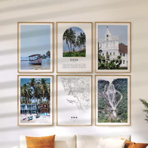May include: Six framed art prints featuring scenes from Goa, India. The images include a boat on the water, palm trees on a beach, a white church, a coastal town, a map, and a waterfall. The frames are made of light-colored wood.