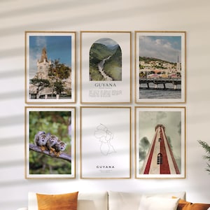 May include: A collection of six framed art prints featuring Guyanese landscapes and wildlife. The prints include images of architecture, a river, a bridge, monkeys on a branch, a map, and a lighthouse. The prints are in wooden frames.