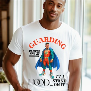 Könnte beinhalten: Weißes T-Shirt mit einem Superhelden-Motiv. Die Grafik zeigt einen Superhelden mit blauem Umhang, rotem und grünem Anzug und dem Text "GUARDING MY HOOD... I'LL STAND ON IT" in Orange und Schwarz.