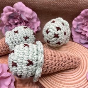 Op de afbeelding: Drie gehaakte ijshoorns met mintgroen ijs en bruine chocolade stukjes. De hoorns liggen op een houten schijf.